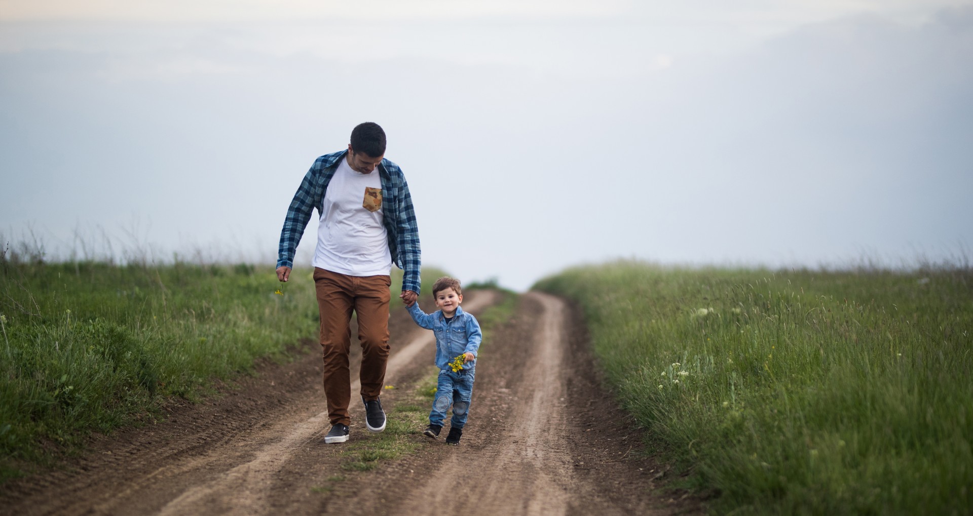 man and child walking on dirt road