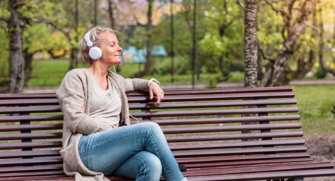 woman sitting on a bench with her eyes closed and listening to music