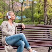 woman sitting on a bench with her eyes closed and listening to music